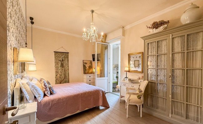 Madonna del Terraglio: camera con copriletto rosa, lampadario di cristallo e armadio a vetri