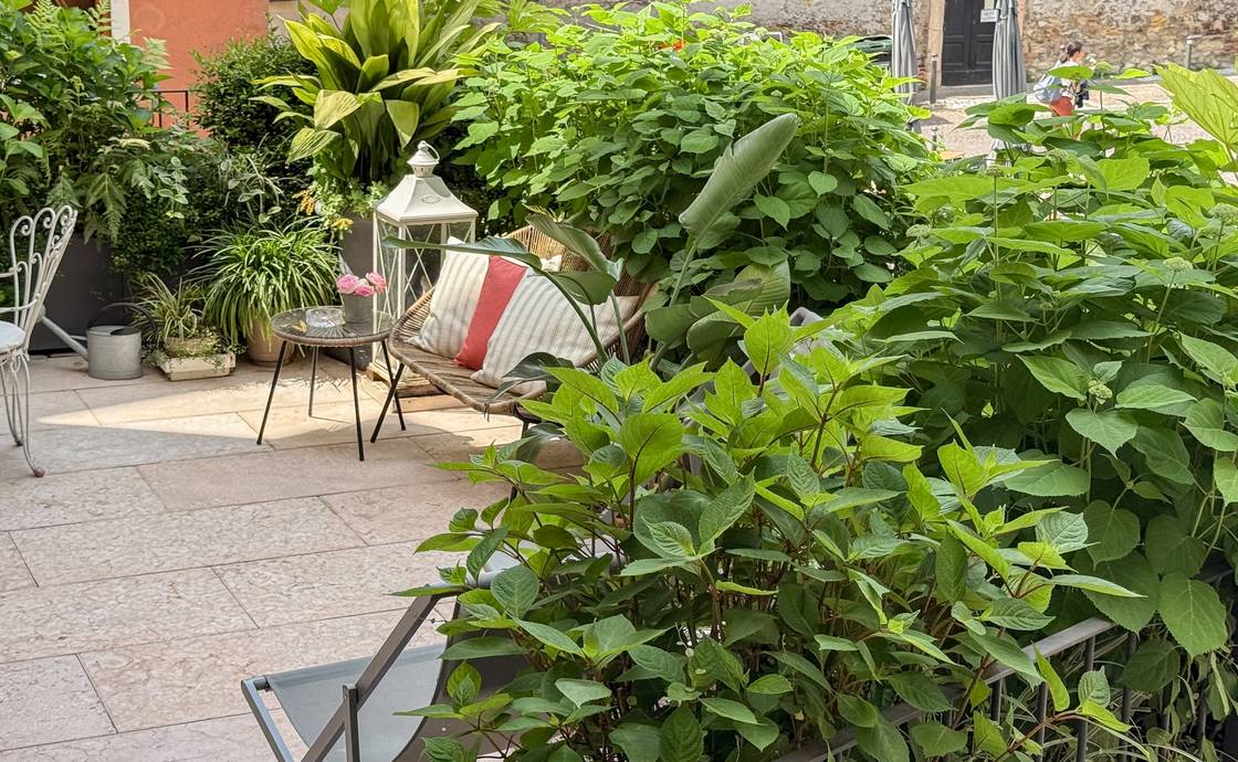 Gepflasterte private Terrasse von Santo Stefano mit weissem schmiedeeisernem Tisch und Stühlen zwischen Topfpflanzen
