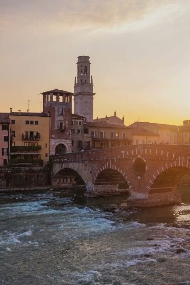 Ponte Pietra at sunset over the Adige, with the bell tower of Verona Cathedral behind the houses