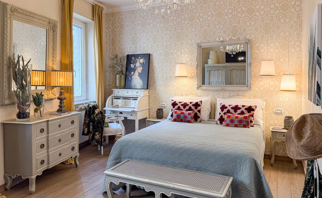 Schlafzimmer in Madonna del Terraglio mit weissem Schreibtisch, Kronleuchter und gelben Vorhängen