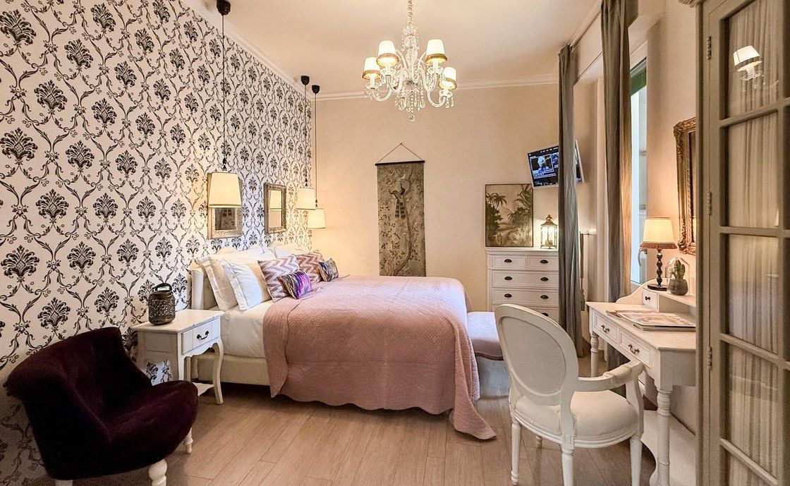 Schlafzimmer in Madonna del Terraglio mit Damasttapete, rosa Tagesdecke und Kristallleuchter