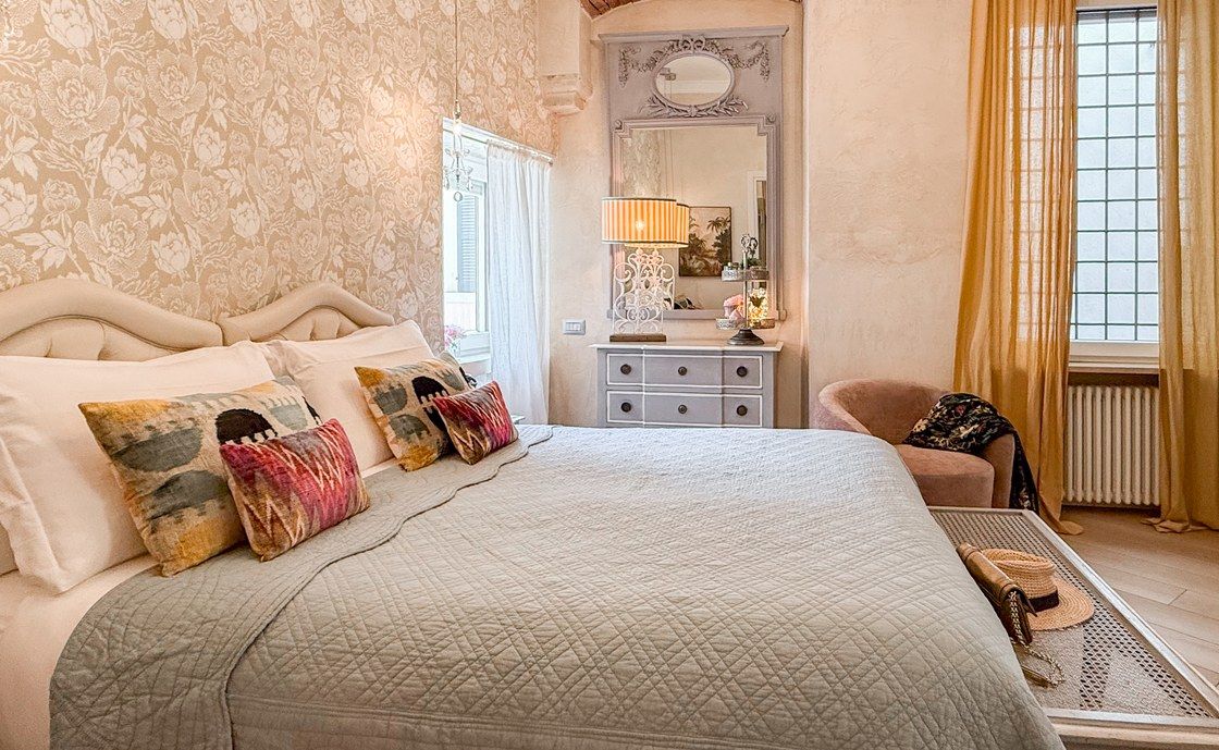 Doppelbett in Santo Stefano mit gepolstertem Kopfteil, gemusterten Kissen und weisser Kommode
