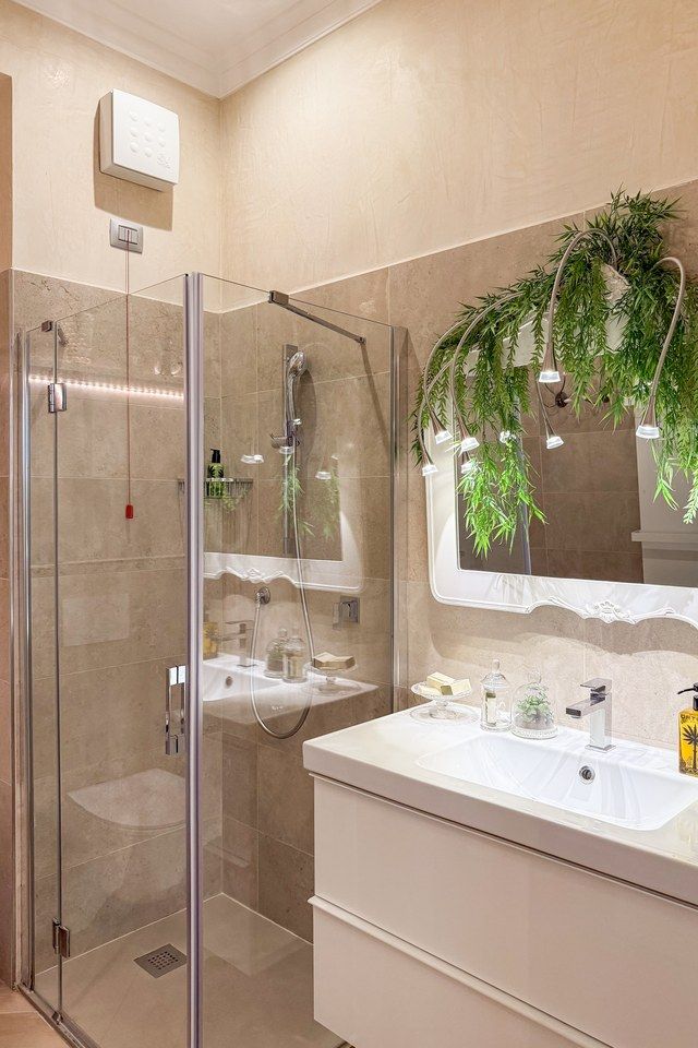 Badezimmer in Santo Stefano mit Glasduschkabine, weissem Waschtisch und einem hängenden Farn